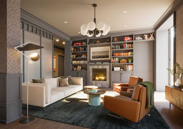 A refined living room with a contemporary-traditional character, featuring built-in dark grey shelving surrounding a fireplace, a pale sofa, cognac leather lounge chairs, a dark area rug, patterned wallcovering, and a sculptural multi-globe pendant light. Natural light enters through large glazing on the right, while a timber sideboard and decorative objects complete the room.