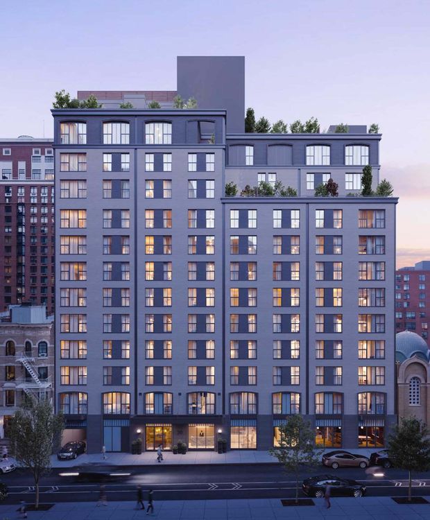 A dusk architectural rendering of a multi-storey urban residential building with a dark blue-grey masonry facade, extensive repetitive windows, stepped rooftop volumes, planted roof terraces, and ground-floor retail or lobby spaces. Adjacent brick buildings and historic-looking neighbouring structures frame the street-facing development.