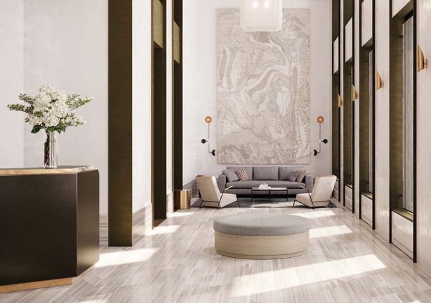A refined, high-ceilinged contemporary living room or lounge with dramatic full-height black-framed glazed and paneled walls, pale timber flooring, and a large decorative marble-like feature artwork or stone surface behind a low grey sofa. A sculptural round upholstered ottoman sits centrally, with two modern lounge chairs, a black console with flowers, integrated wall lighting, and abundant daylight creating a luxurious, gallery-like atmosphere.