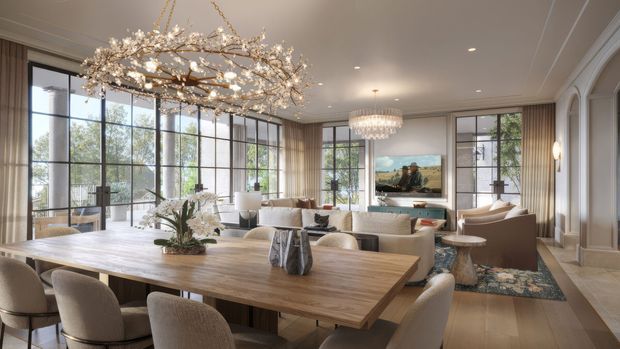 An elegant open-plan dining and living room with a large light-wood dining table and upholstered chairs in the foreground, flowing into a refined lounge area. Full-height black-framed glazing brings in abundant natural light, while fluted wall panelling, arched architectural detailing, layered neutral furnishings, and statement crystal and branch-like chandeliers create a luxurious contemporary-classic atmosphere.