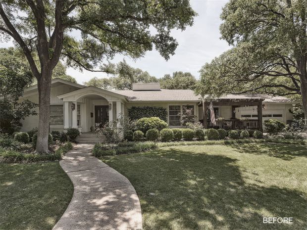 Front exterior view of a single-storey suburban house set behind a broad lawn and mature trees. The home has a low-pitched gabled roof, light-coloured horizontal siding, a covered entry porch with simple columns, and a curved concrete walkway leading to the front door. The image is presented as a “BEFORE” renovation view, with established landscaping and a shaded, traditional residential character.