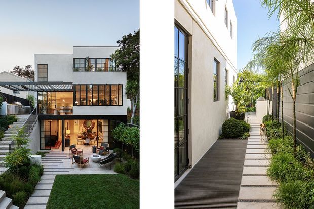 A contemporary multi-level residence shown in two exterior views. The left view shows a white rendered facade with extensive black-framed glazing, a rooftop or upper-level terrace, covered outdoor dining, and a landscaped courtyard with stepped paving and lawn. The right view shows a narrow side passage with white rendered walls, dark framed windows and doors, timber-look decking, concrete stepping slabs, planted borders, and a grey masonry boundary wall. The overall design is clean-lined, urban, and strongly connected to landscaped outdoor spaces.