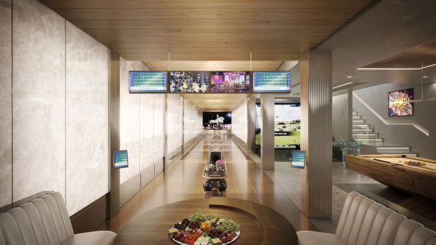A sophisticated entertainment and lounge interior with a central bowling lane extending into the distance, overhead digital scoreboards, a dining table with food in the foreground, upholstered seating, a pool table to the right, and a staircase leading to an upper level. The space features warm timber ceilings, pale stone or concrete-look wall panels, reflective flooring, ribbed columns, and integrated entertainment screens.