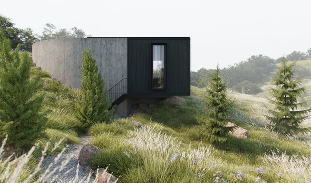 A compact modern pavilion or cabin set within a landscaped, sloping natural site. The building has a stark rectangular form with a dark vertically ribbed exterior, a curved or faceted raw concrete wall, a narrow vertical window, and appears slightly elevated above the ground. Ornamental grasses, shrubs, small conifers, and rocky terrain surround the structure, creating a minimalist architecture-in-landscape composition.