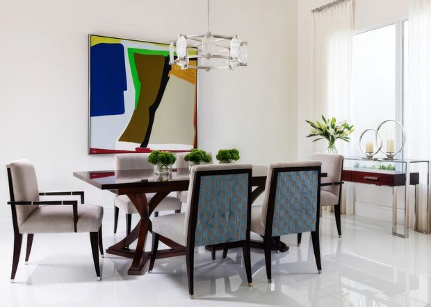 Bright, refined dining room with a polished white floor, dark wood dining table, upholstered dining chairs, a contemporary geometric chandelier, sheer floor-to-ceiling curtains, and a large colourful abstract artwork. A slim console with decorative plants sits beside the window.
