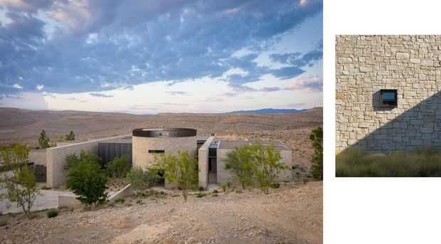A contemporary desert residence set in a sparsely vegetated rocky landscape, viewed from an elevated position. The low, rectilinear building has pale stone masonry walls, a rounded cylindrical central volume, flat roofs, and narrow dark openings. A secondary image shows the textured stone facade with a small square window and strong angular shadow. The scene has a stark, sculptural character against an expansive desert horizon.