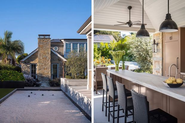 Split image showing a refined coastal-style residence and its covered outdoor entertaining area. The left side presents a stone-clad facade with gabled roof forms, blue-grey window frames, landscaped planting and a pale paved or gravel forecourt. The right side shows an outdoor kitchen or bar with a long pale stone-look counter, integrated sink, cabinetry, woven bar stools, black pendant lights, a ceiling fan and a white-lined pitched ceiling, opening to a landscaped garden.