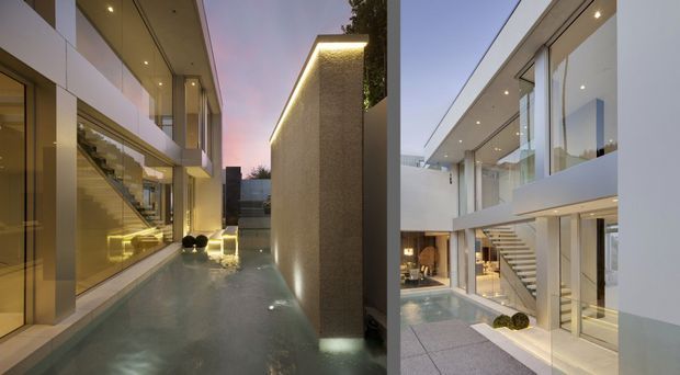 Diptych showing a sleek contemporary multi-storey residence organized around a narrow reflective water courtyard. Floor-to-ceiling glazing, white rendered volumes, clean roof overhangs, concealed lighting, and an internal staircase create a refined indoor-outdoor connection. The left view is a dusk courtyard scene with illuminated water and textured wall; the right view shows the bright courtyard and open-plan interior circulation.