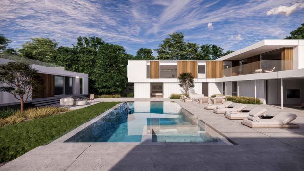 A contemporary multi-wing residential property arranged around a long rectangular swimming pool and expansive paved terrace. The main two-storey building has crisp white rendered volumes, extensive dark-framed glazing, warm vertical timber screening, and deep roof overhangs. A separate low pavilion sits across a landscaped lawn, with mature trees forming a private backdrop. Outdoor loungers and seating occupy the poolside terrace.