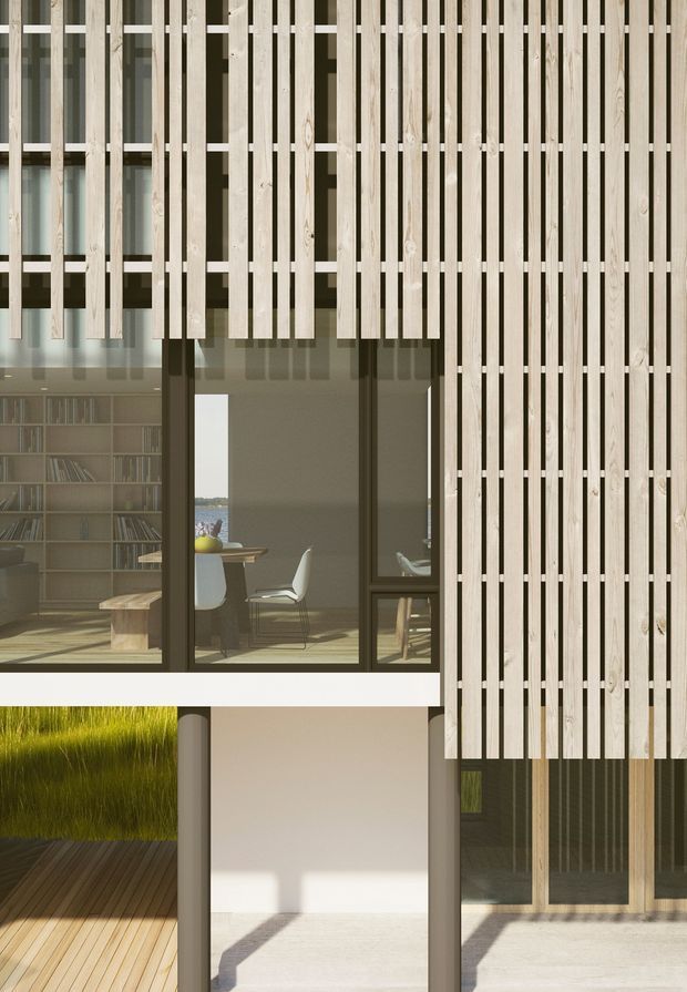 Exterior architectural view of a contemporary multi-level building with a prominent vertical timber batten screen over dark-framed glazing. The screening creates a layered facade with varied spacing and cantilevered sections. Through the glazing, a dining/work area and shelving are visible, while the lower level includes a timber deck, planted area, recessed entry or wall zone, and additional glazing. Strong sunlight creates crisp shadows across the pale rendered surfaces and decking.