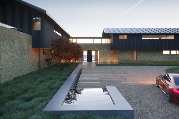 Exterior architectural view of a contemporary multi-wing building arranged around a landscaped courtyard and driveway. The structure combines dark vertical-clad upper volumes, pale rough masonry walls, narrow horizontal glazing, and pitched metal roofs. A linear reflecting pool or water feature leads toward the central entrance, with textured planting and a partially visible car in the foreground.