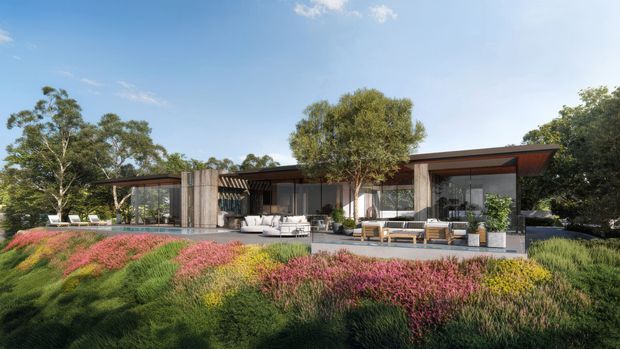 Single-storey contemporary house set within a landscaped garden, featuring a low, broad roofline, extensive floor-to-ceiling glazing, dark slender window frames, timber-toned soffits, and a mix of solid concrete or stone-like feature walls. Outdoor lounge and dining areas connect directly to the garden, while dense ornamental planting fills the foreground.