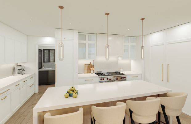 Bright, spacious contemporary white kitchen with extensive shaker-style cabinetry, a large central island with integrated seating, a professional range cooker, and three slim pendant lights. Light timber flooring and warm wood accents add contrast to the predominantly white and cream palette.