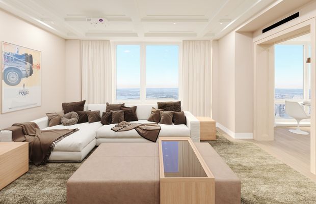 Bright, refined living room with a large cream L-shaped sectional sofa, oversized upholstered ottoman, neutral textured rug, timber coffee table, and layered brown cushions. Floor-to-ceiling windows and an open glazed doorway provide expansive water and city views. The room has detailed white ceiling panels, recessed lighting, full-height curtains, and a calm contemporary coastal feel.