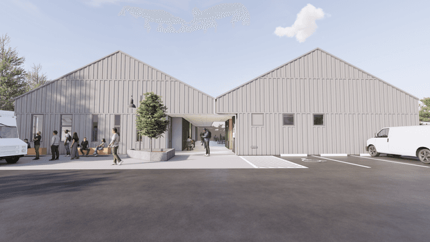 A photorealistic architectural rendering of a contemporary low-rise commercial development composed of two adjoining gabled volumes. The buildings have light vertical ribbed cladding, large glazed openings on the left volume, small rectangular windows and service doors on the right, and a covered pedestrian connection between them. The foreground is a broad asphalt parking and access area with marked spaces, several white commercial vehicles, people near the entrance, and sparse landscaping. The scene is bright and clean with a simple industrial-commercial character.