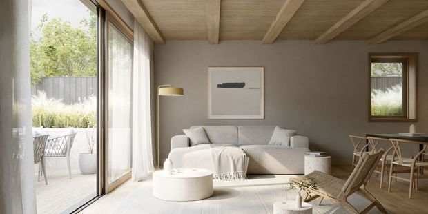 A bright, refined open-plan living and dining space with full-height glazed doors opening to a patio and garden. The room features a neutral upholstered sofa, round coffee table, woven lounge chairs, a dining table, large-format light flooring, and a warm timber-lined ceiling with exposed beams. Soft daylight and restrained furnishings create a calm, natural contemporary atmosphere.