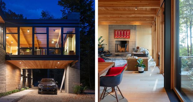 A split architectural photograph showing a modern timber-clad house in a wooded setting at dusk and its warm contemporary living room interior. The exterior features a glazed upper level with a projecting timber soffit, while the lower level forms a sheltered carport with a parked vehicle. Inside, the living room has extensive glazing, exposed timber ceiling boards, pale flooring, a fireplace with tiled surround, mid-century-inspired seating, and a red artwork accent.