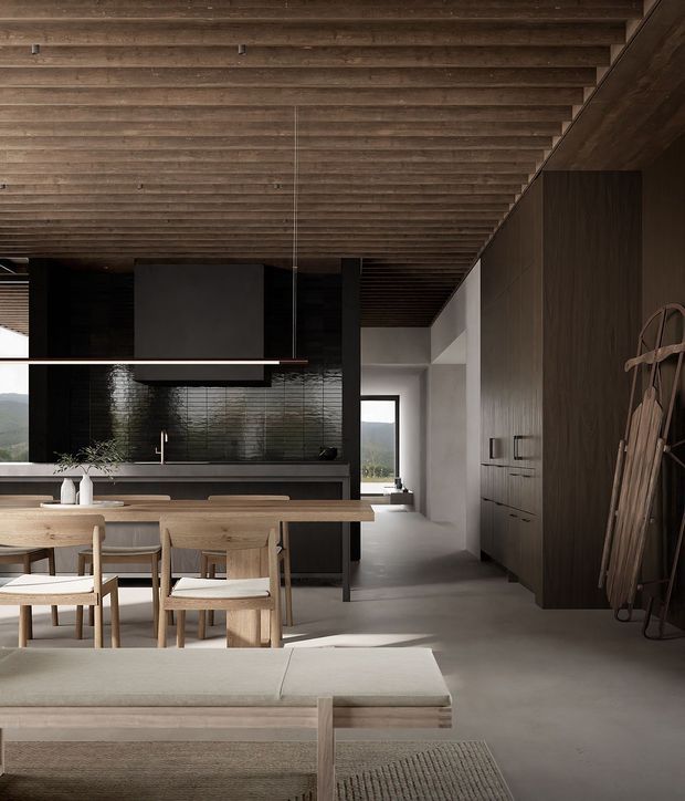 A warm, contemporary open-plan kitchen, dining and living space. The room features a dark kitchen with a glossy black tiled splashback, a long timber dining table with timber chairs, extensive dark timber cabinetry, a pale upholstered bench seat, and a dramatic ceiling of closely spaced exposed timber beams. Large openings provide views toward a green landscape, while minimalist dark and neutral finishes create a refined, grounded atmosphere.