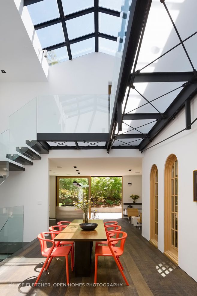 This Mark English Architects's project encompasses a remodel and a small addition to an existing two-story family home in San Francisco’s Cow Hollow neighborhood. Seen here, the modernization process involved removing most of the second floor and creating a double height dining space at the heart of the home. A cantilevered steel and glass staircase wraps the room and a new skylight above floods the void with natural light, emulating the feeling of an atrium.