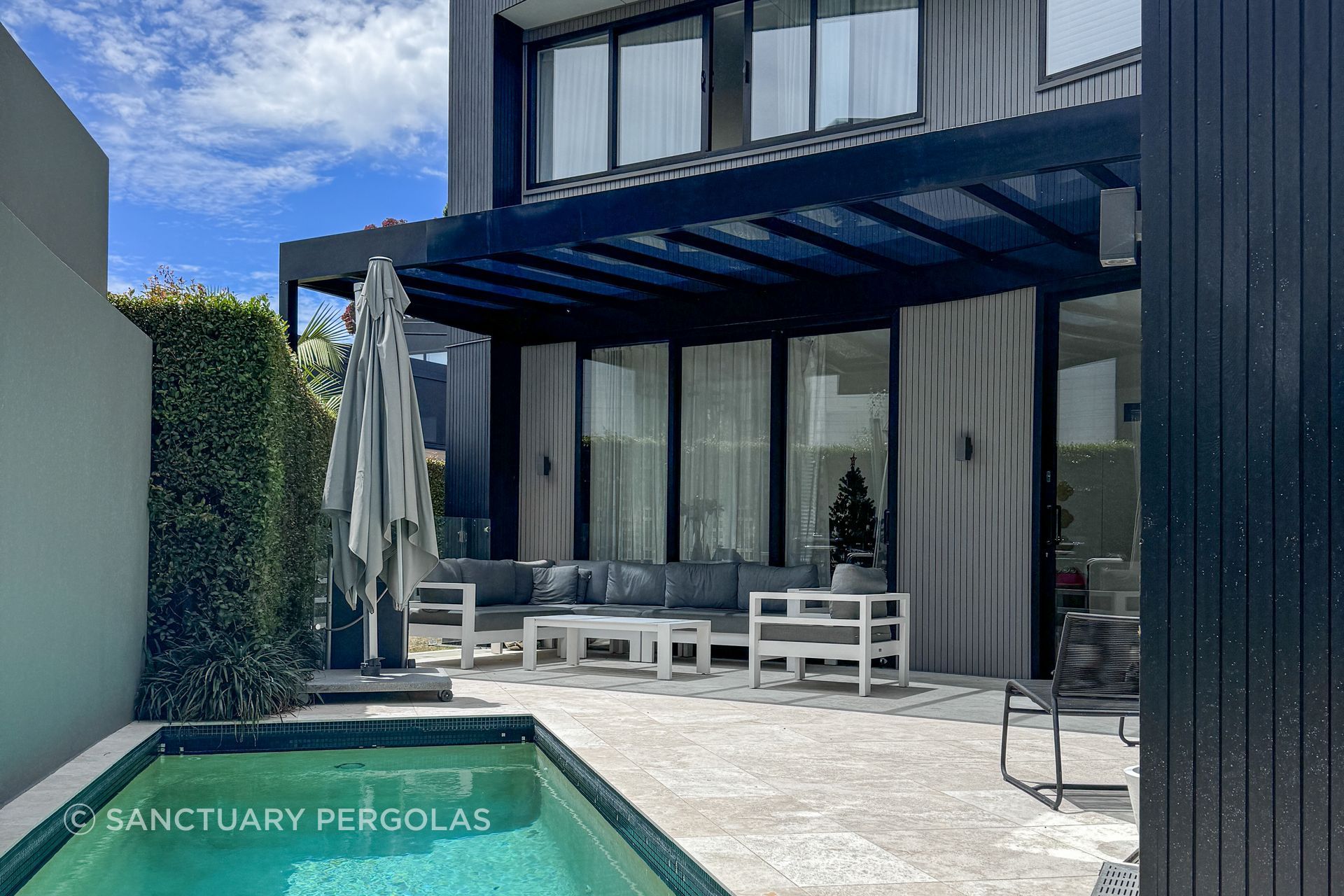 A dramatic black pergola creates a sheltered outdoor entertainment space.