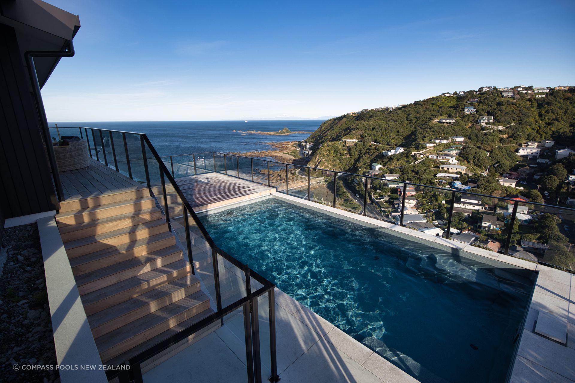 Stunning hillside pool installation on top of a steep hill in Wellington featuring innovative Maxirib™ technology, breathtaking views of the Cook Strait, and a focus on easy maintenance with a self-cleaning system and automated features.