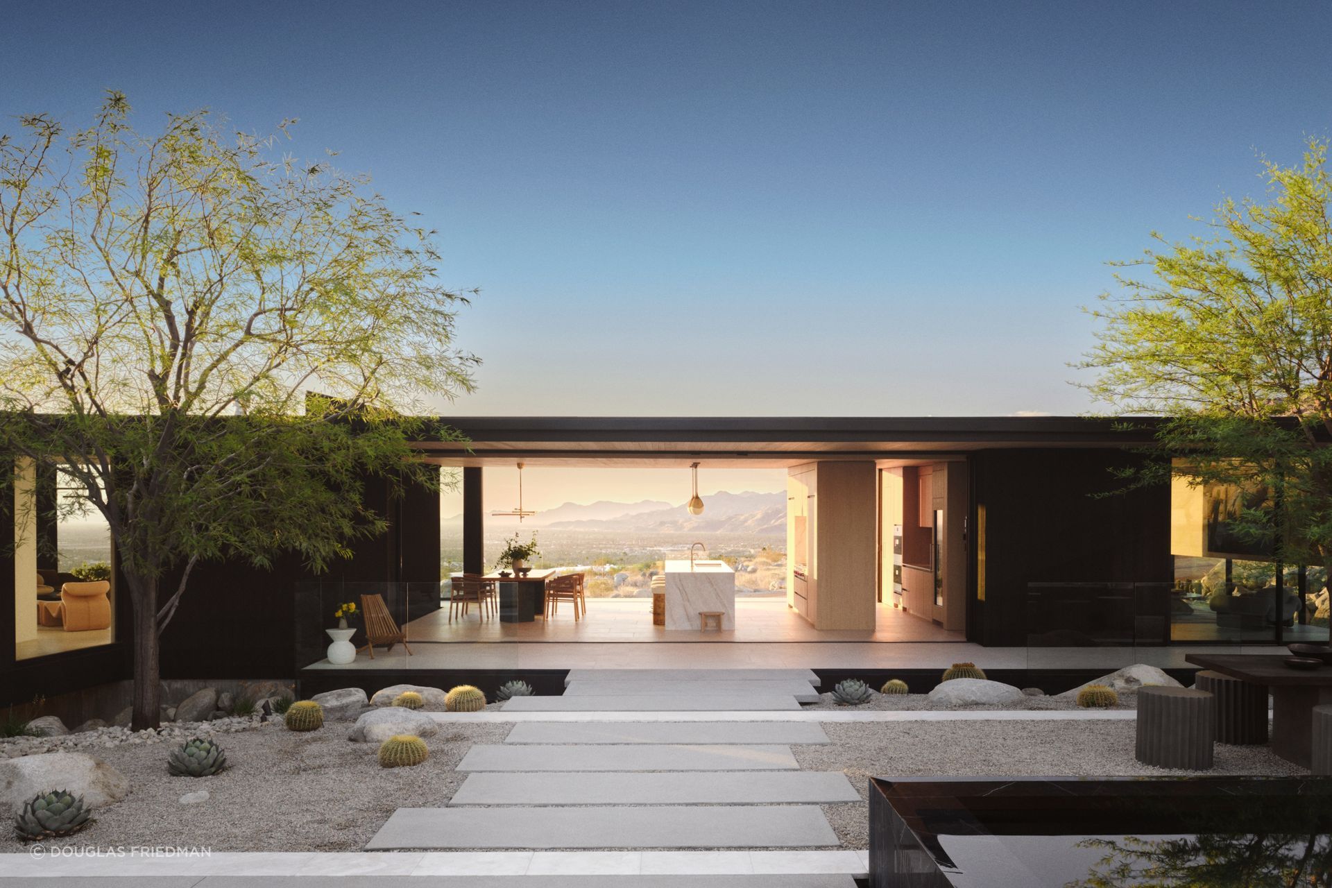 The concept for Jill Lewis Architecture's project is analytical, shaped by a study of the site’s contours, arroyos, sun, and winds. Its boomerang form, shifted forward on the lot, cradles a private garden at the rear. The main volume floats above the desert, anchored on three board-formed concrete pedestals that rise from the land like volcanic rock.
