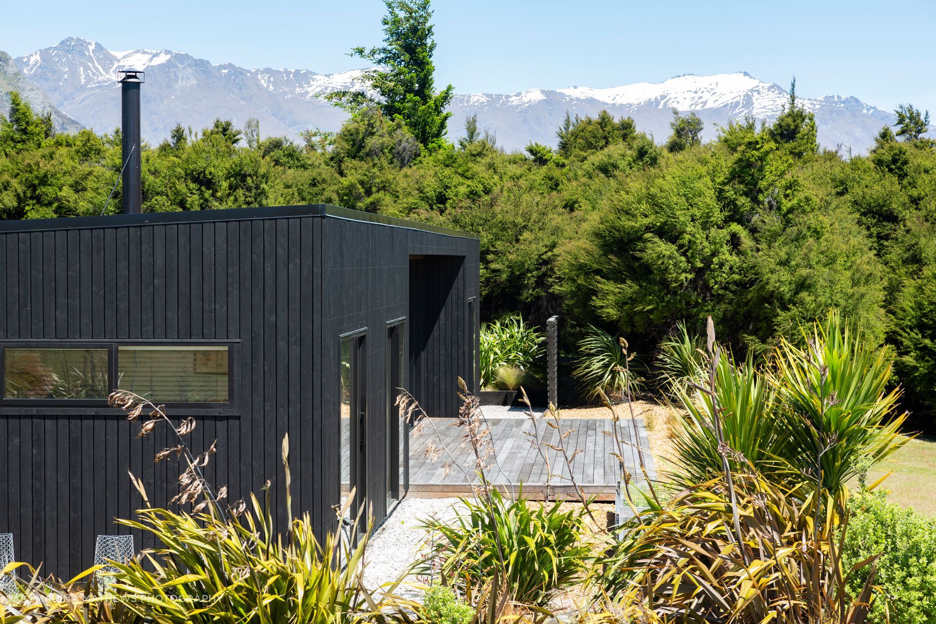 Snow-covered mountains backdrop the char-black home.