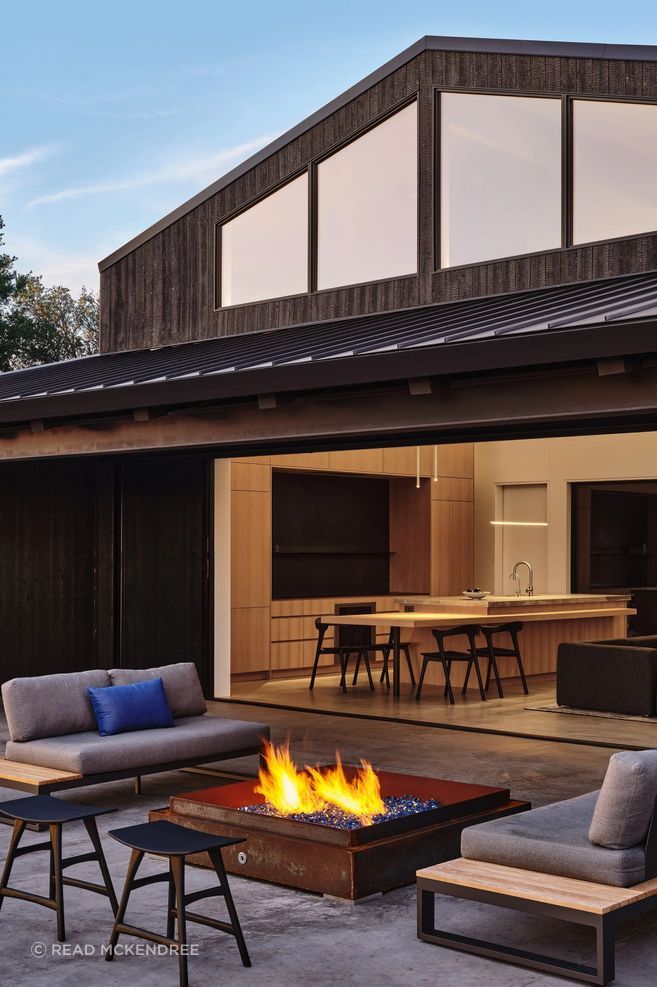 Expansive openings connect the kitchen and living spaces with a sheltered outdoor terrace.