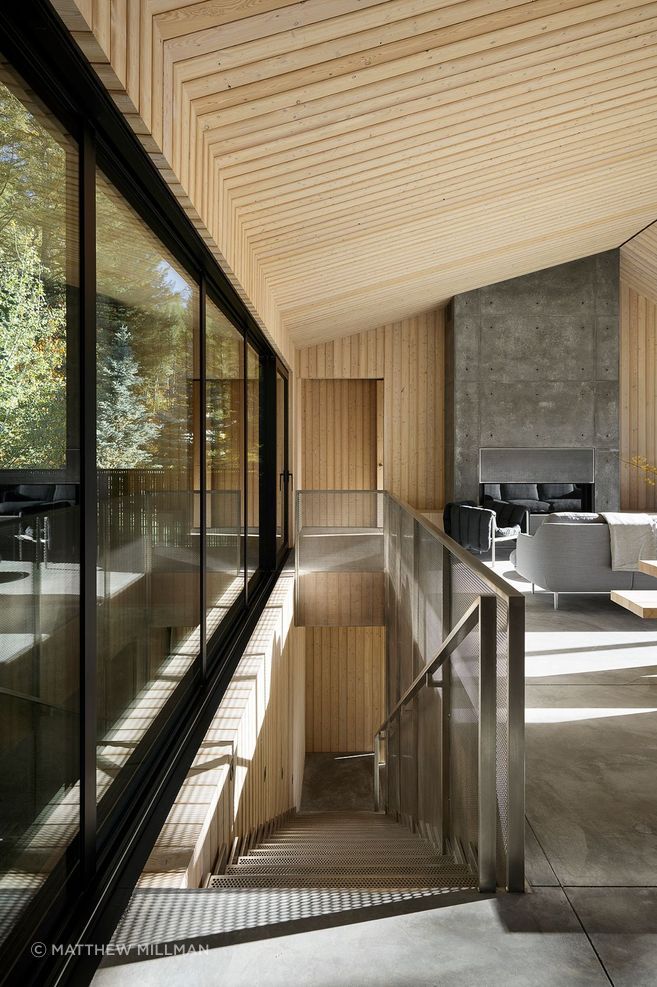 The upper level features an open-plan living, dining, and kitchen area along with four bedrooms. A floating staircase—a perforated stainless steel structure—serves as both a functional and sculptural element.