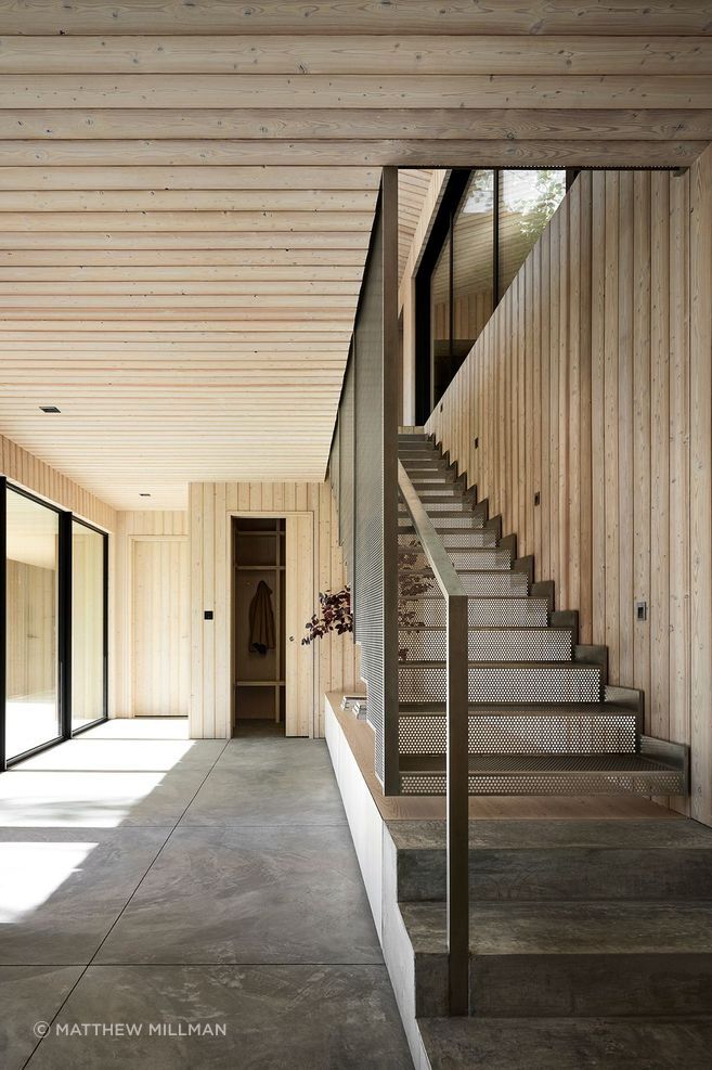 The two-story layout strategically positions the main living areas on the upper floor to maximize views, while the lower level houses practical spaces such as a garage, mudroom, and gym.