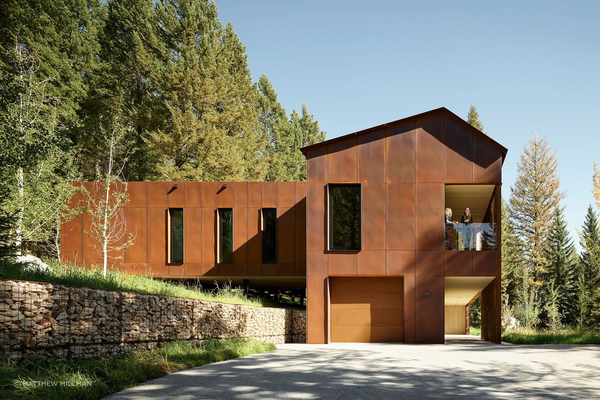 The structure is both embedded in and hovering above the landscape, with a compact footprint and an elevated bedroom wing supported by slender columns that touch the hillside lightly.