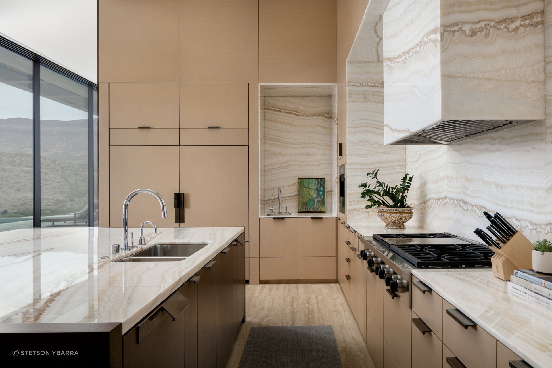 The kitchen combines handcrafted detailing with a restrained material palette of stone, bronze, and reconstituted oak, reflecting the enduring character of the desert.