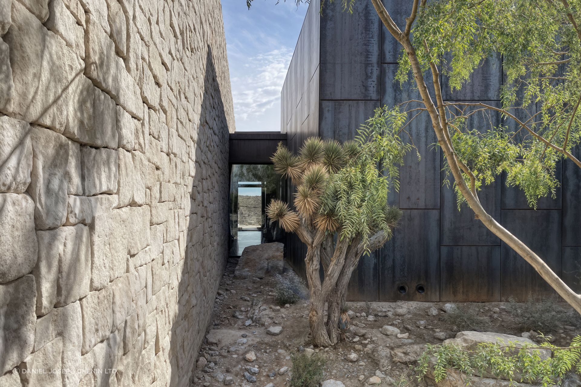 Landscape passages weave between stone walls and native vegetation, transforming circulation into an immersive experience of the desert environment.