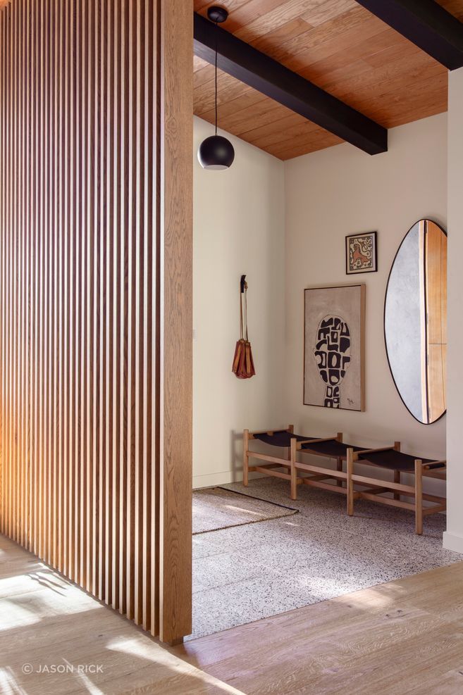 A vertical timber screen defines the entry while allowing light to filter through the open interior.