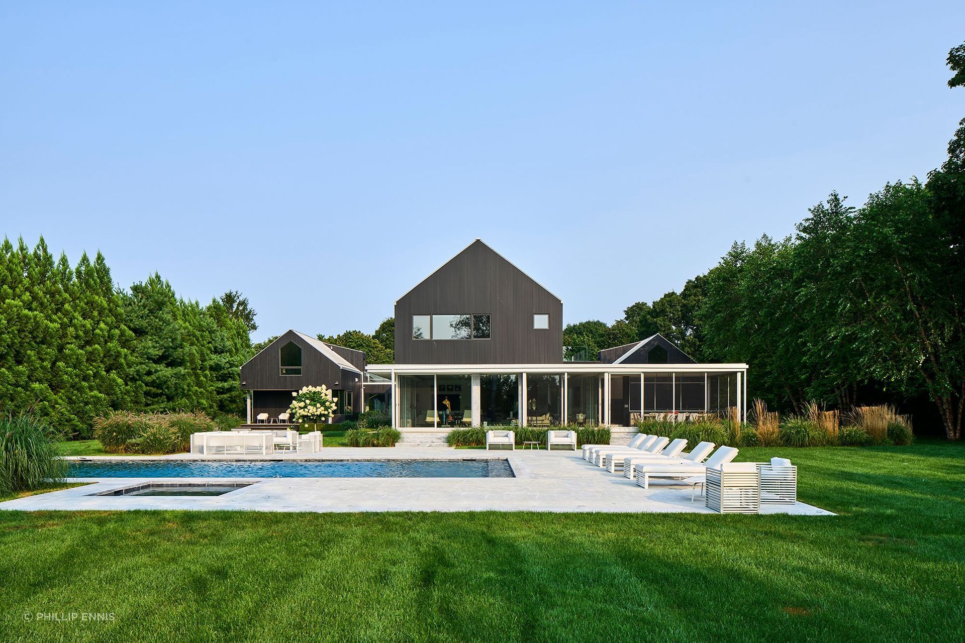 The architectural concept draws inspiration from the adjacent agricultural buildings, particularly the linear repetition of gabled greenhouse forms. This influence is translated into a composition of three primary gabled volumes aligned toward the street, connected by breezeways.