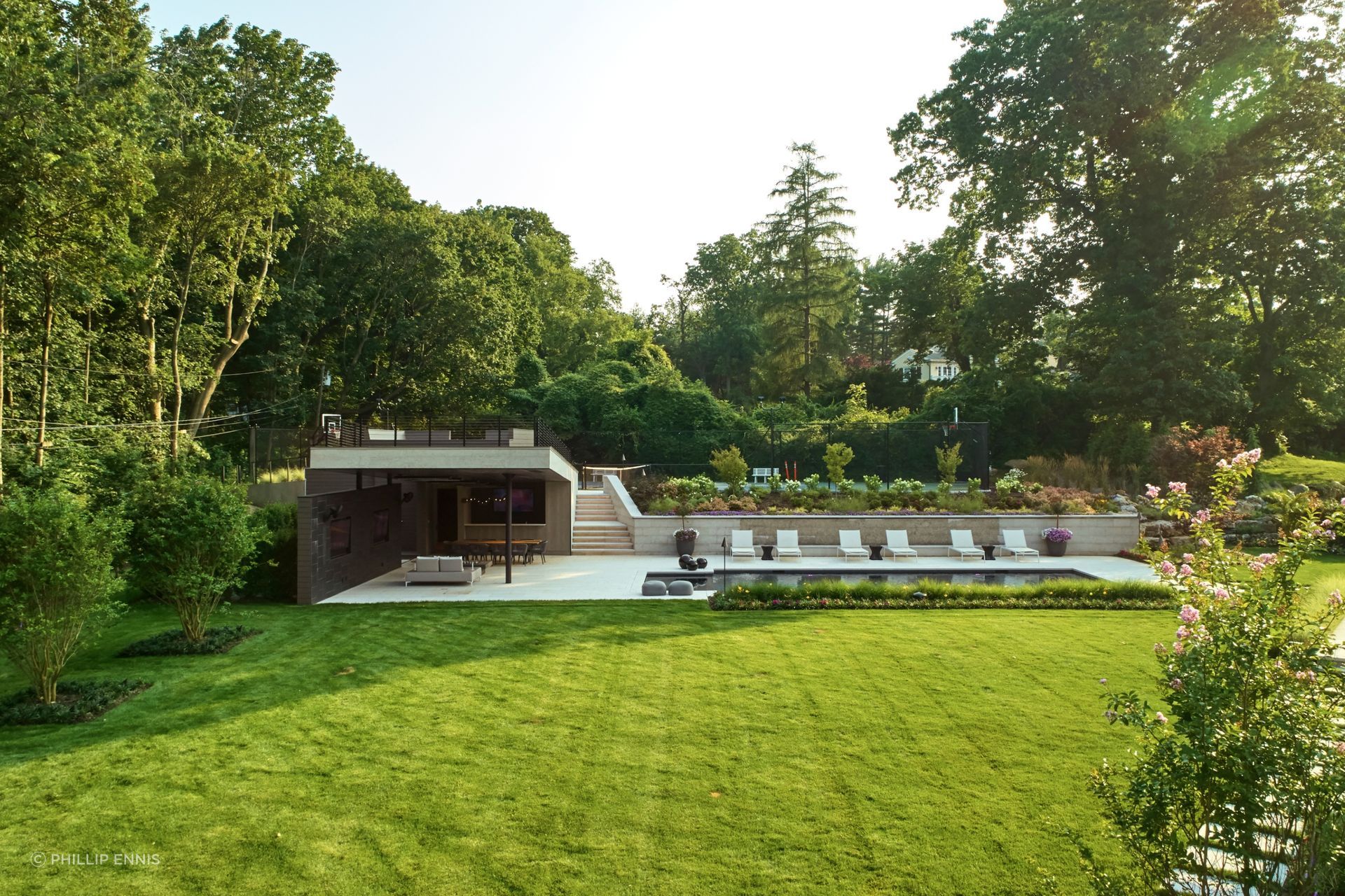 The plan for a "Pagoda" style outdoor area takes advantage of the client's large backyard space and elevated topography to weave together the pool/hot tub, cabana space, and tennis court. The inside portion of the cabana has a lounge area, bath/changing room, television, and a bar that services the covered outdoor seating.