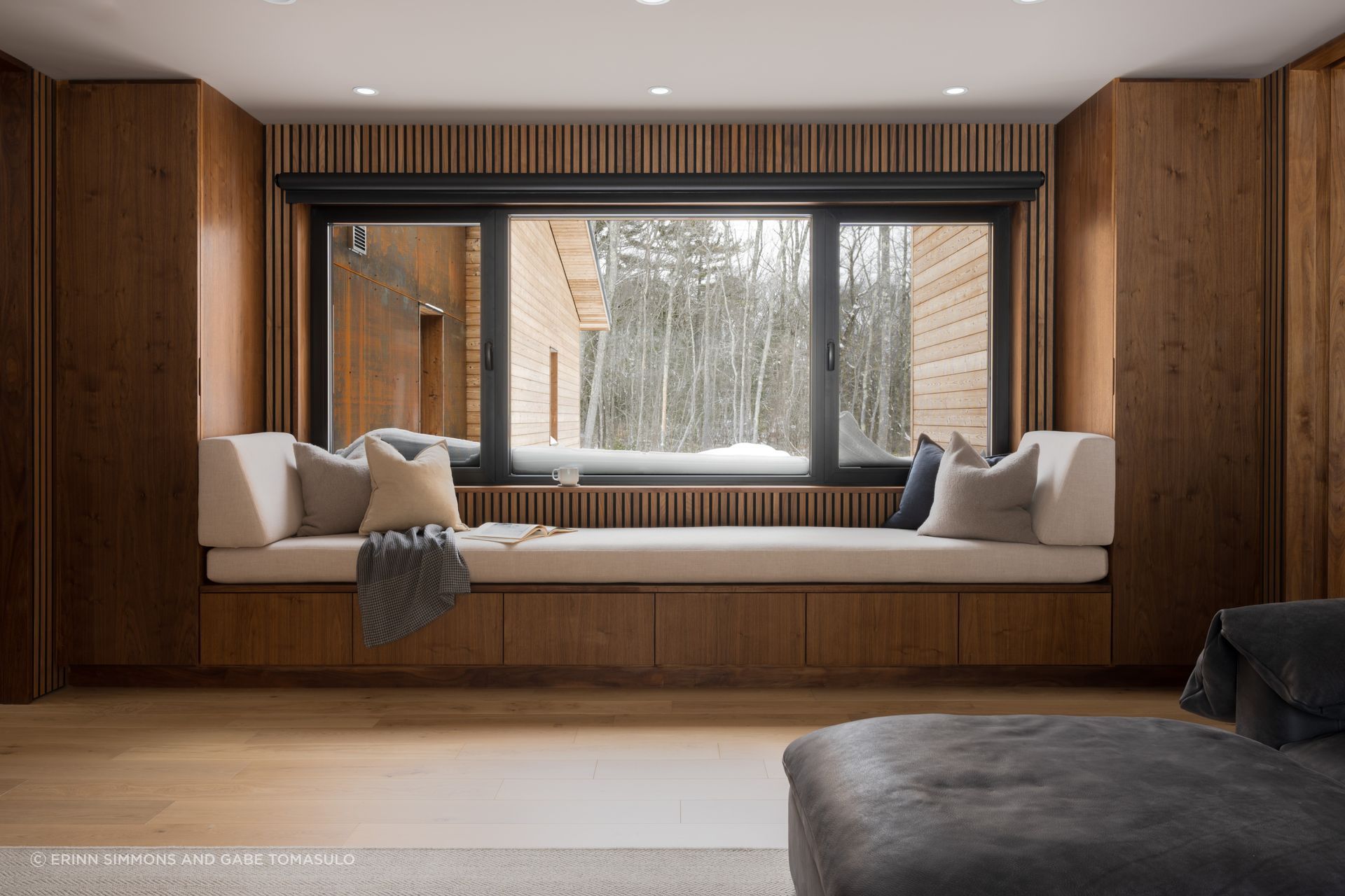 A deliberately cozy, lower-ceilinged space finished in walnut casework and paneling functions as the home’s TV room.