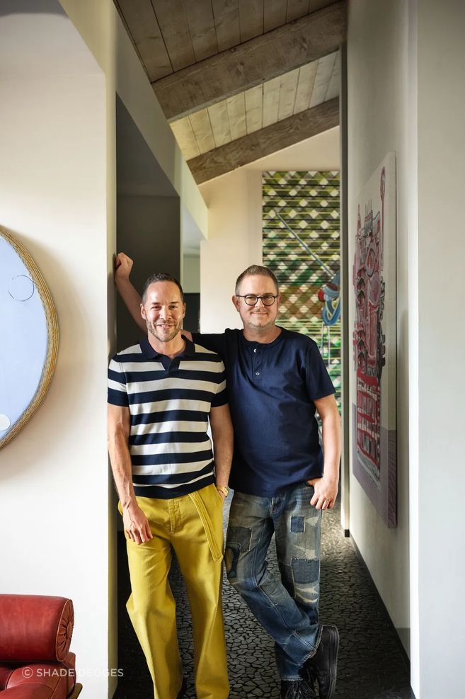 AD100 designer Ryan Lawson (right) with Sean Robins, cofounder of Studio Van Den Akker, at the couple’s home in Rancho Mirage, California; painting by Otis Jones Art: Otis Jones. Juan Uslé. Ry David Bradley.