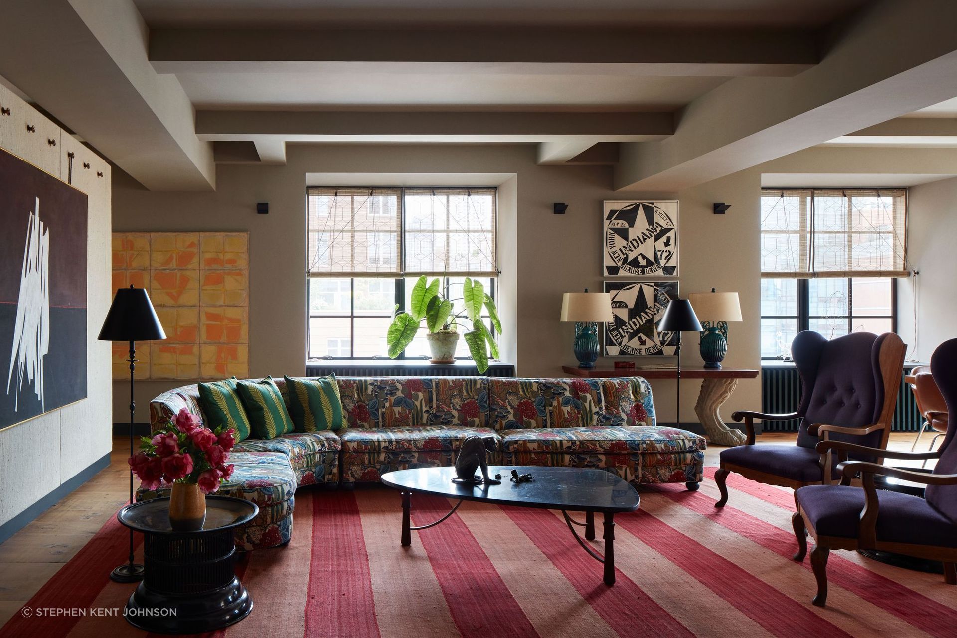 The sitting area’s snaking vintage sofa mingles with two antique Danish armchairs; the black-and-white artworks on the far wall are by Robert Indiana.