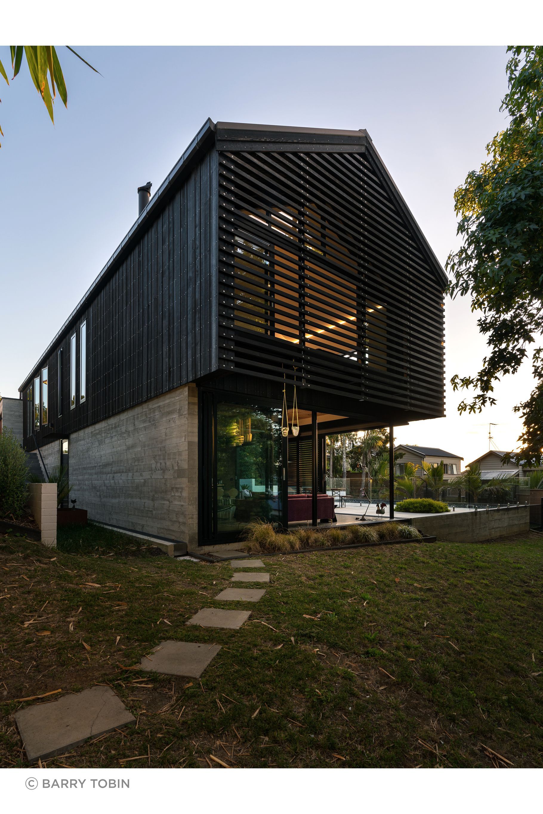 The family home of architect Clive Chapman of Pacific Environments Architects in Auckland. The gable roof, the vertical siding, the small windows and the strength of the concrete and corten steel are all references to the industrial shed feel that Clive wanted.