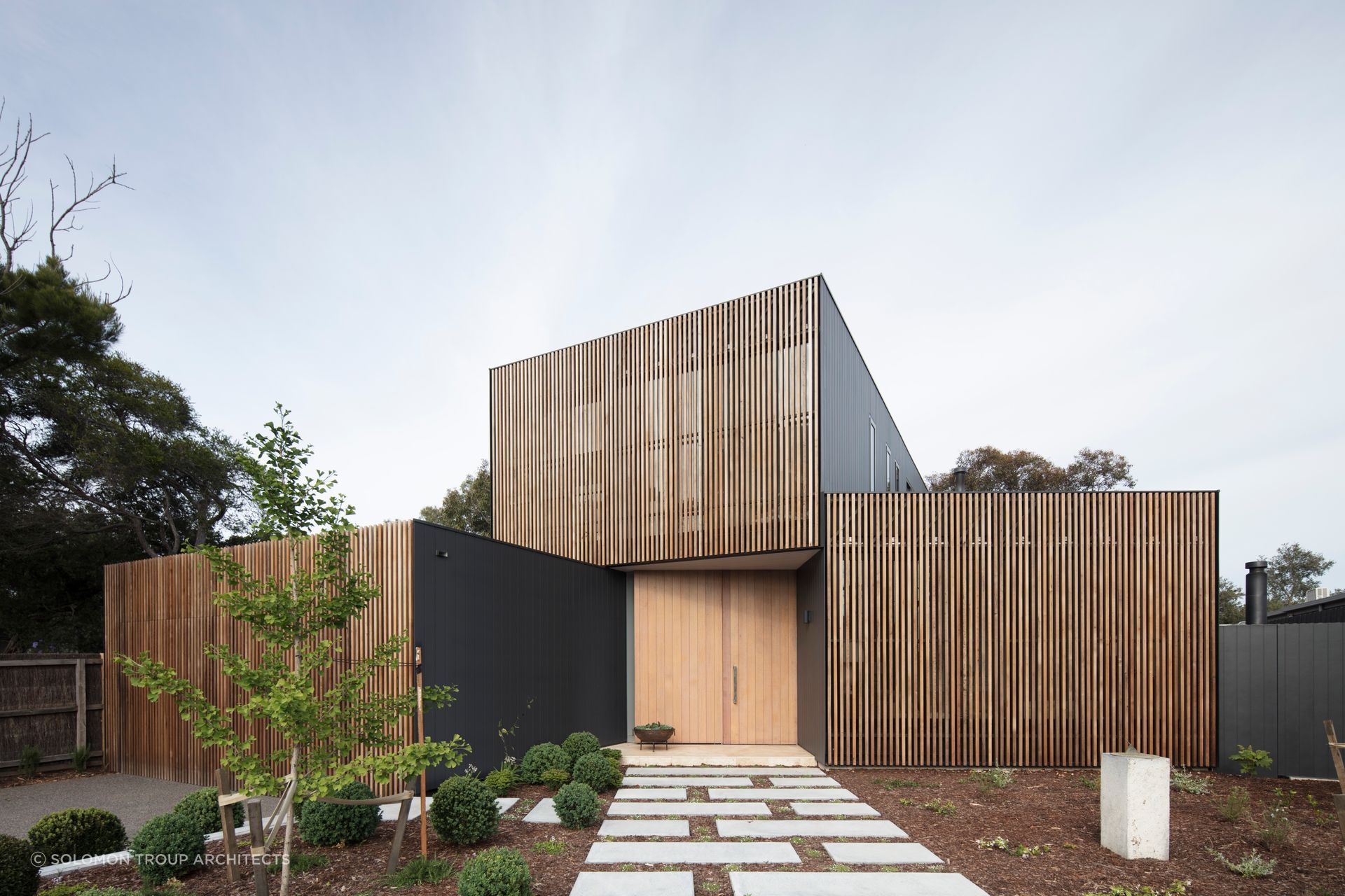 This home's facade mixing Western Red Cedar screens with a matte black metal finish creates a unique visual identity. Photography: Ben Hosking
