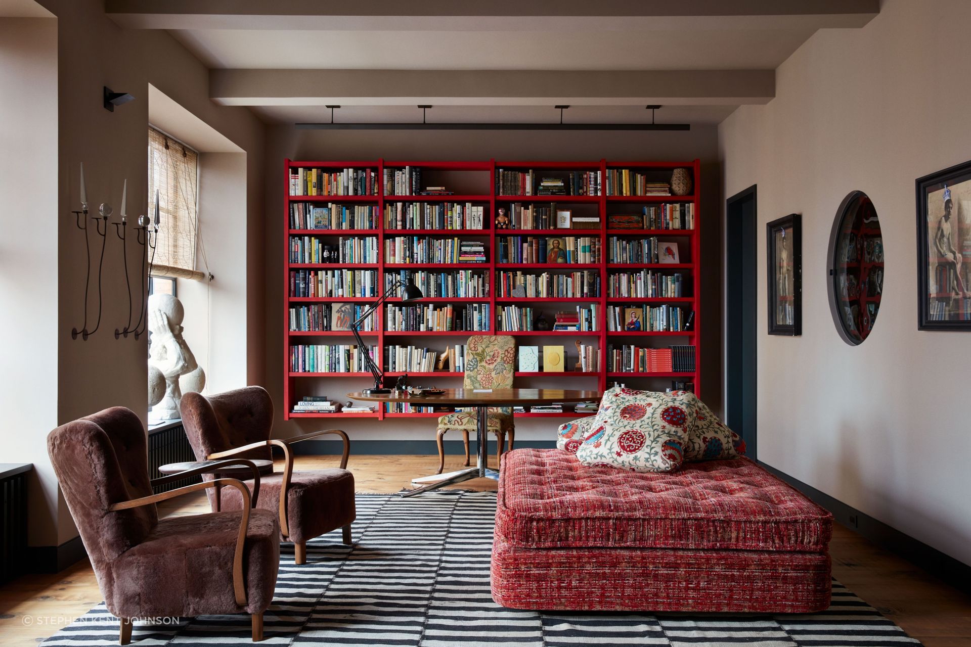 Designed by Ryan Lawson, the Manhattan loft of Stephen Henderson and James LaForce features a library with a floating bookcase by Green River Project and a custom daybed upholstered in a Claremont velvet; the armchairs are vintage Danish and the wall sculptures (left) are by R.W. Russell.