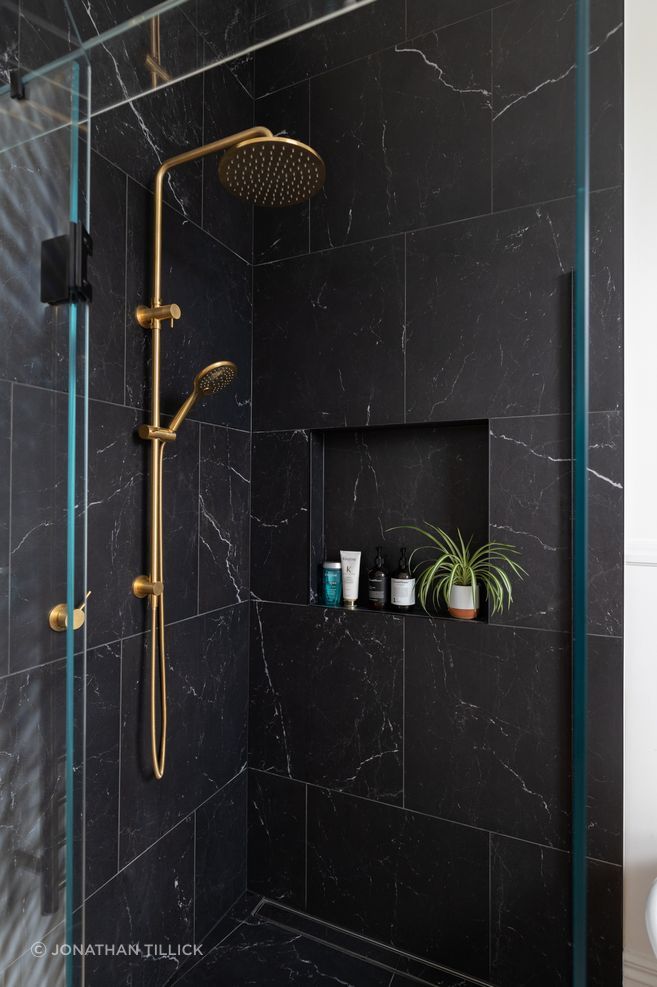 Brass tapware contrasts with the black tiles and complements the home's heritage features.