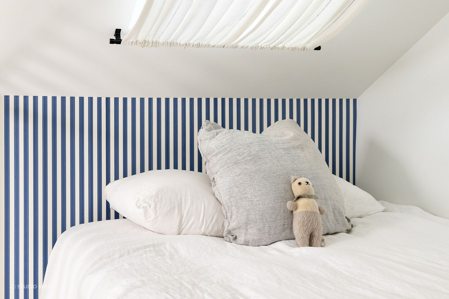 The blue-striped Farrow &amp; Ball wallpaper brings a fun sailor's theme to the bedroom.