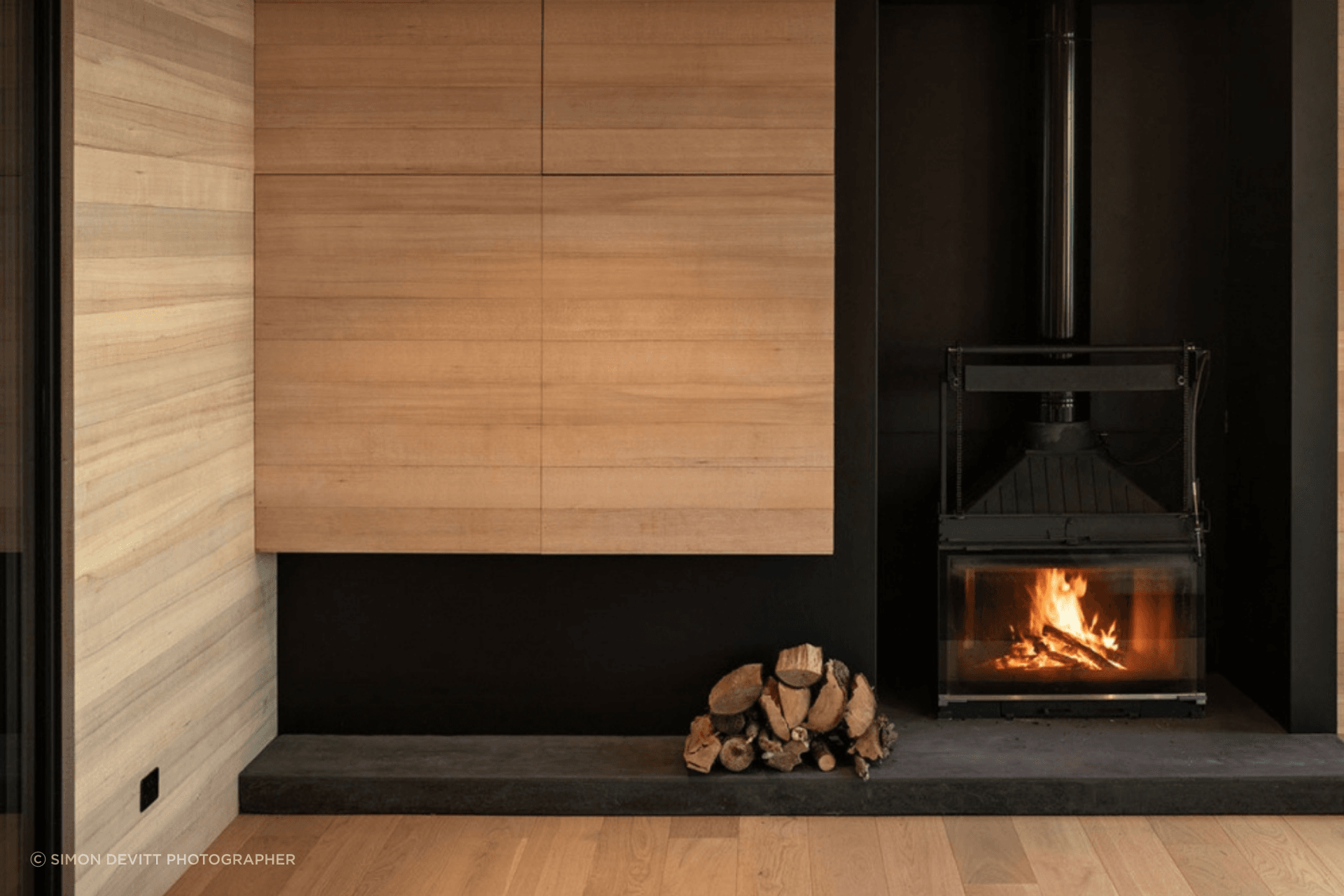Off the dining space, the living area features plush seating, a wood-burning fireplace, and a television hidden in the cabinetry. 