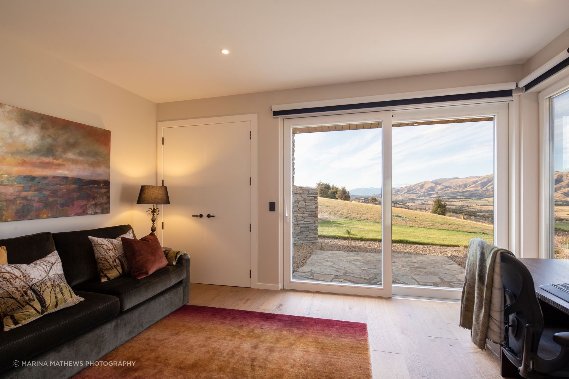 The study/guest room featuring oak desk and custom-designed couch offers stunning views of the landscape.