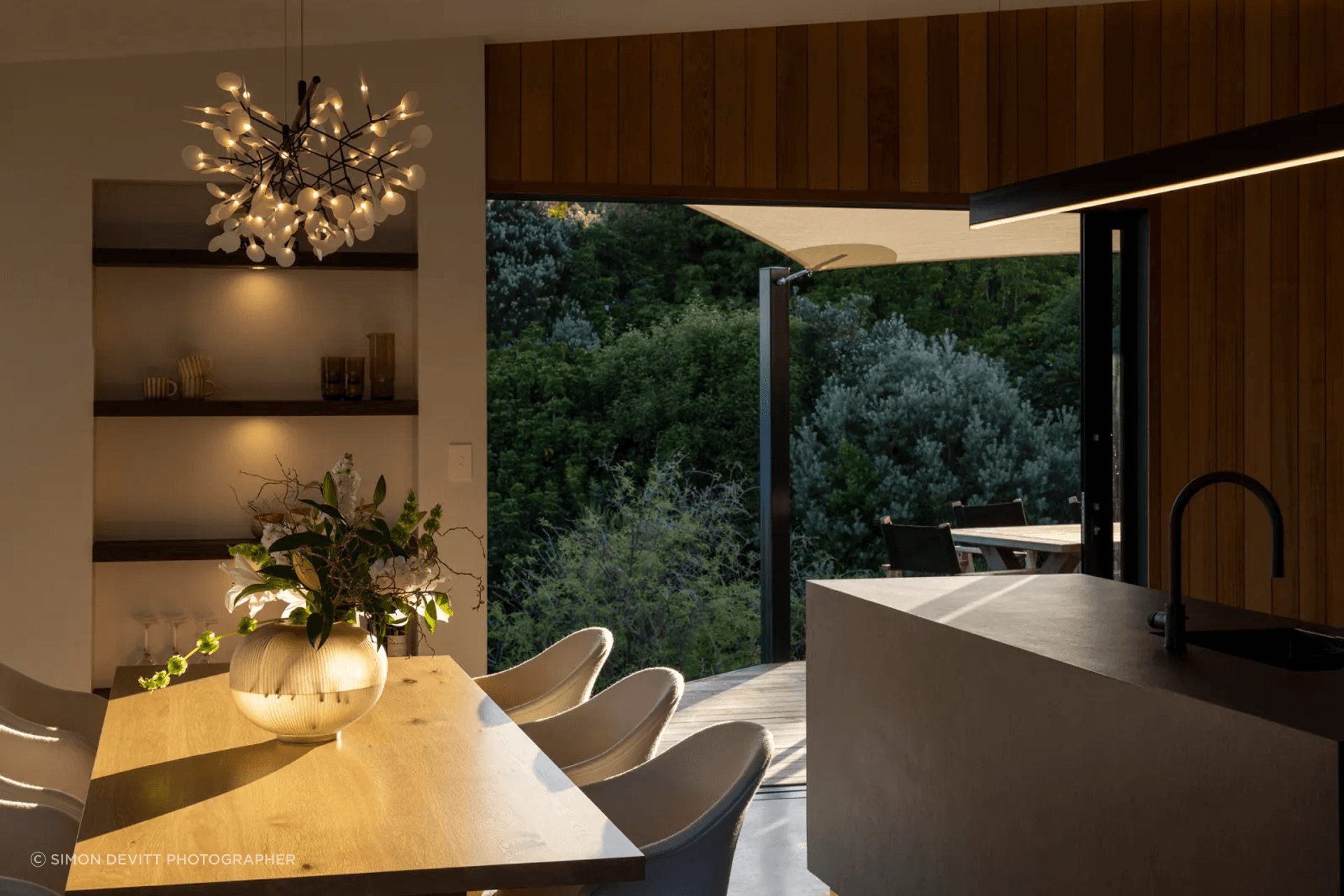 The open-plan kitchen and dining room, extending into the quiet surrounds with a sheltered outdoor living space.