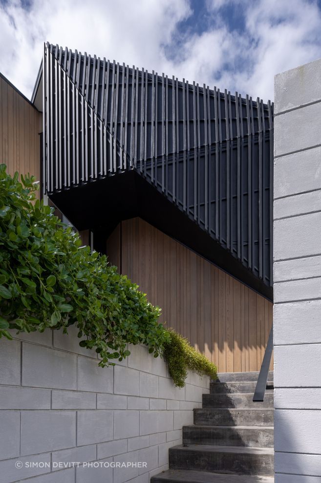 Dark trapezoidal shapes are flanked by pillar-like forms clad in cedar.
