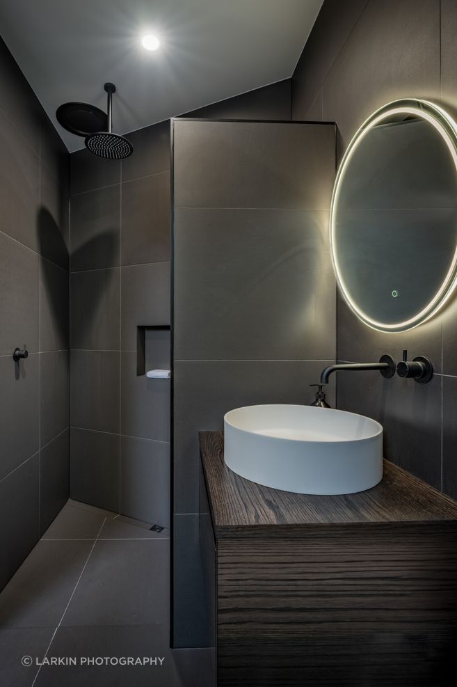 A guest bathroom and bedroom were decided on late in the design and were tucked in behind the angled garage. “That  created an interesting shape and the shower shows that.”