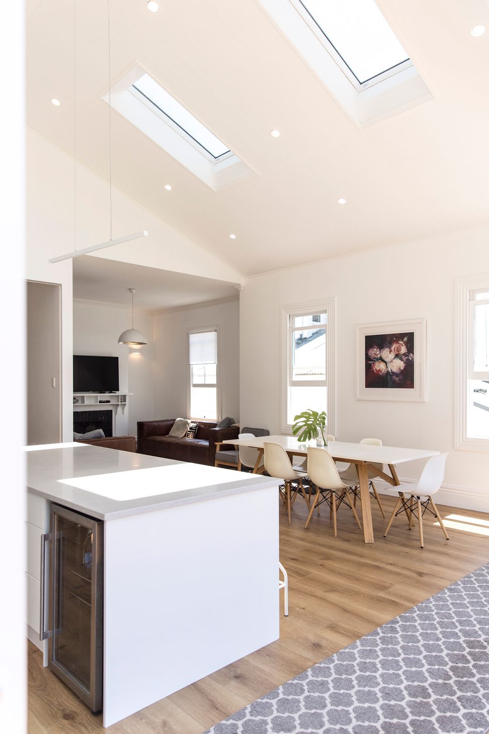 Dual skylights flooding the new addition with light — the open-plan kitchen and dining at Grey Lynn Villa, looking back through to the original lounge beyond. Macfie Architecture.